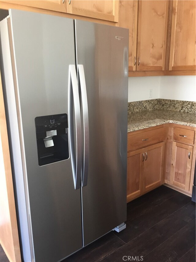 kitchen featuring dark hardwood / wood-style flooring, light stone counters, and stainless steel fridge