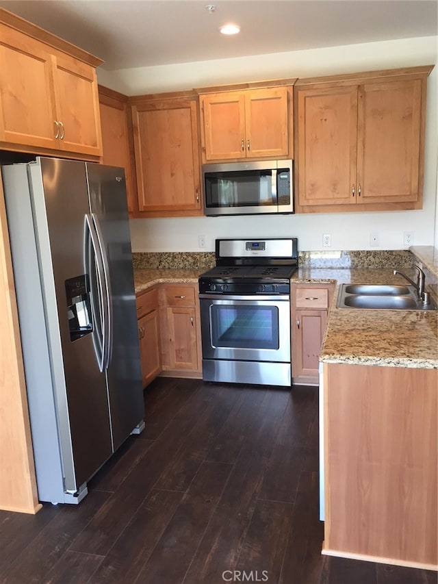 kitchen with light stone countertops, sink, dark wood-type flooring, and stainless steel appliances