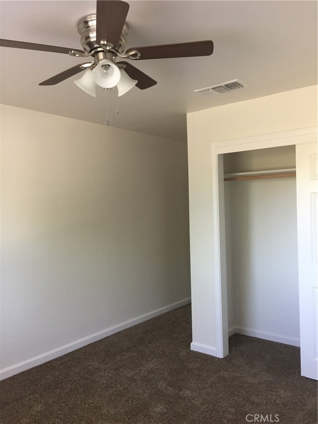 unfurnished bedroom featuring a closet, dark colored carpet, and ceiling fan