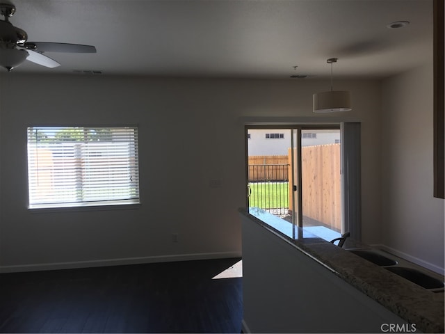 spare room featuring dark hardwood / wood-style flooring, ceiling fan, sink, and plenty of natural light