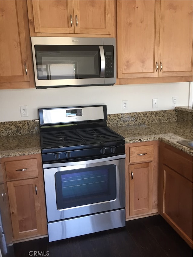 kitchen featuring light stone countertops, stainless steel appliances, and dark wood-type flooring