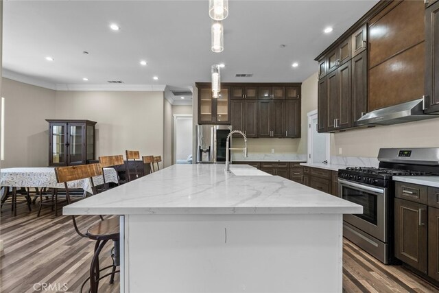 kitchen with a large island with sink, stainless steel appliances, a breakfast bar area, and exhaust hood