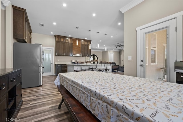 bedroom featuring stainless steel fridge, dark hardwood / wood-style flooring, and ornamental molding