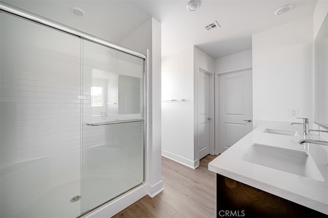 bathroom with hardwood / wood-style floors, walk in shower, and vanity