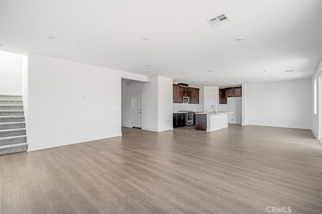 unfurnished living room with sink and hardwood / wood-style floors