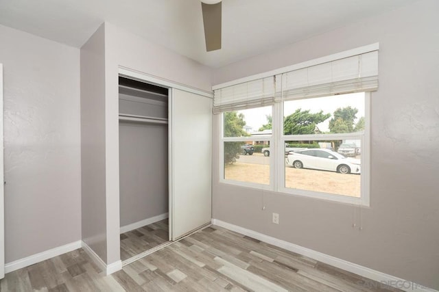 unfurnished bedroom featuring ceiling fan, light wood-type flooring, and a closet