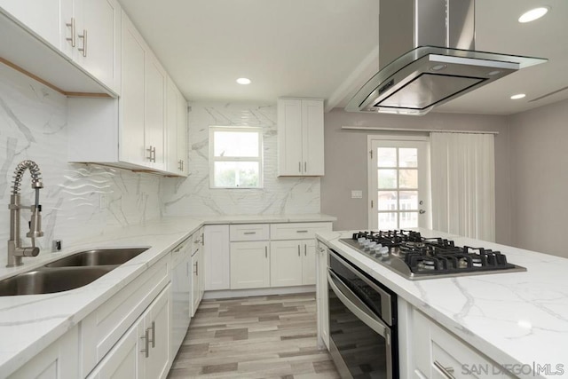 kitchen with island exhaust hood, stainless steel appliances, a wealth of natural light, and sink