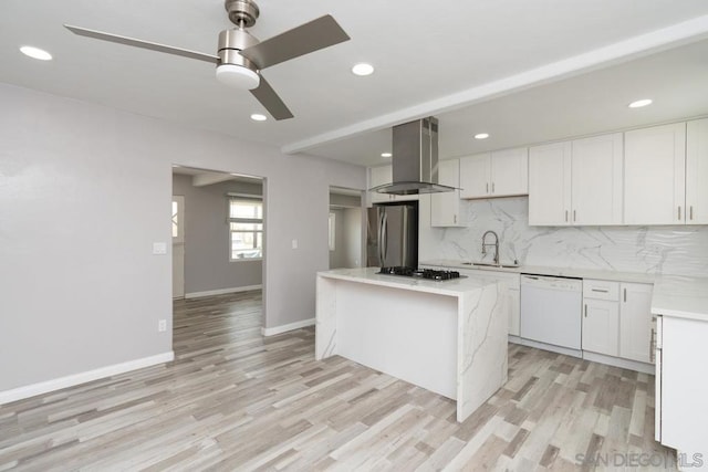 kitchen featuring white cabinets, stainless steel appliances, a kitchen island, and wall chimney range hood