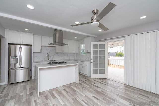 kitchen featuring white cabinets, wall chimney exhaust hood, stainless steel appliances, and light hardwood / wood-style flooring