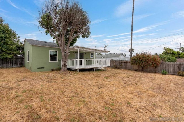 back of property with a lawn and a wooden deck