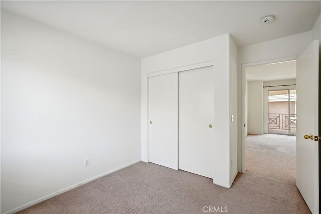 unfurnished bedroom with light colored carpet and a closet