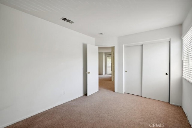 unfurnished bedroom featuring light colored carpet and a closet