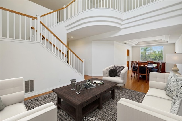 living room featuring dark hardwood / wood-style flooring, a tray ceiling, and a high ceiling