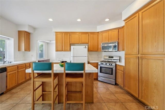 kitchen featuring a kitchen island, appliances with stainless steel finishes, light tile patterned floors, and a kitchen bar