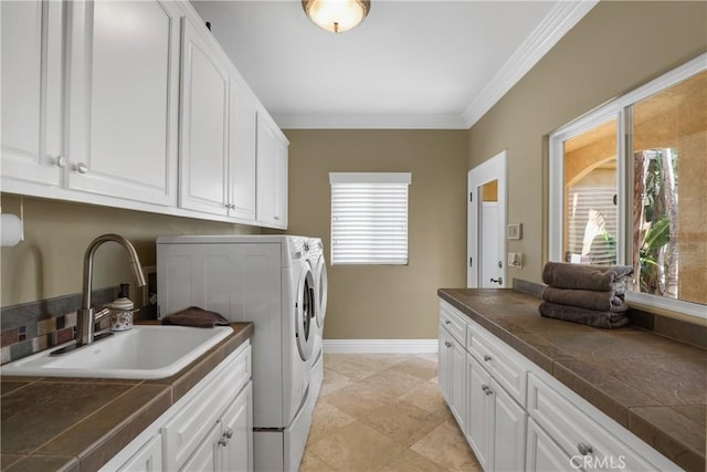 laundry area with a sink, baseboards, washer and dryer, ornamental molding, and cabinet space