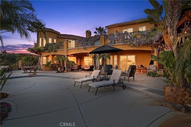 exterior space featuring a patio, a balcony, and stucco siding