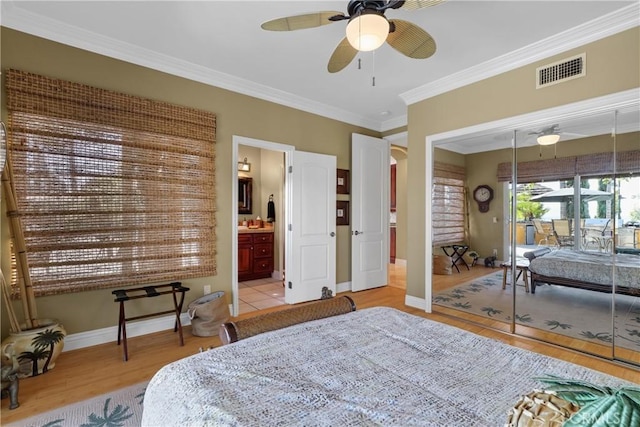 bedroom with crown molding, visible vents, ensuite bathroom, light wood-type flooring, and baseboards