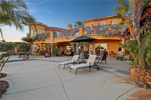 back of property with a patio area, a balcony, and stucco siding