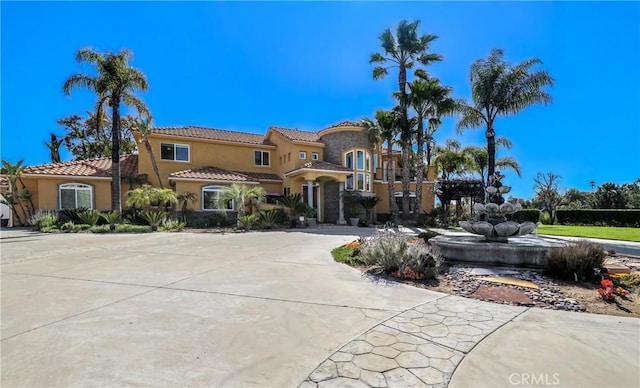 mediterranean / spanish-style house featuring driveway, a tiled roof, and stucco siding