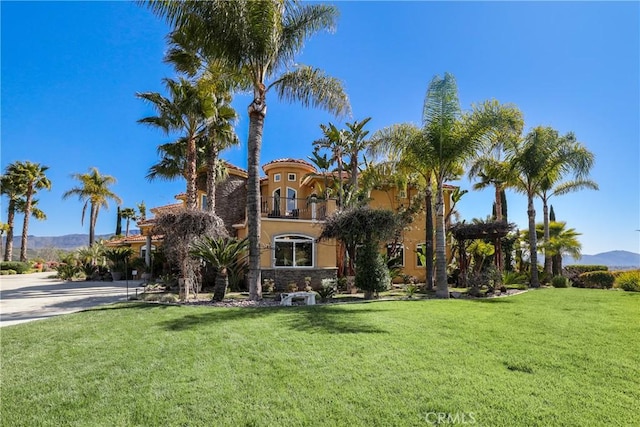 mediterranean / spanish-style home featuring driveway, a balcony, a mountain view, and a front lawn