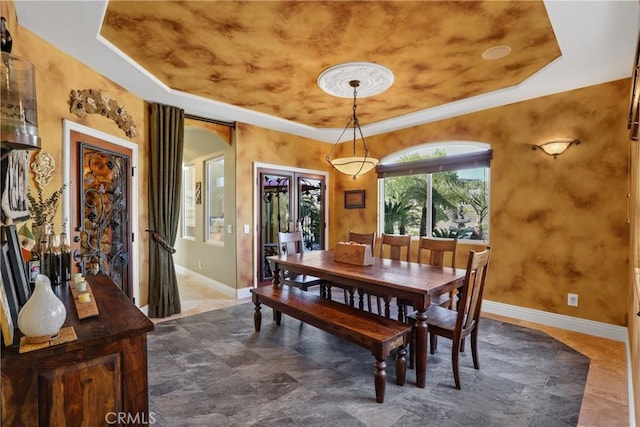 dining space featuring french doors, a raised ceiling, and baseboards