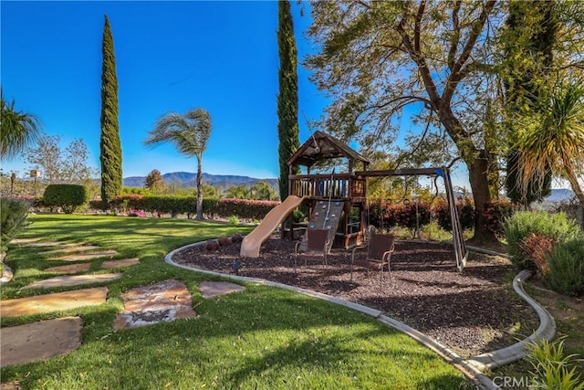 community jungle gym featuring a mountain view and a yard