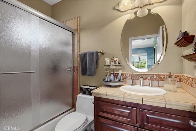 bathroom with enclosed tub / shower combo, vanity, and toilet