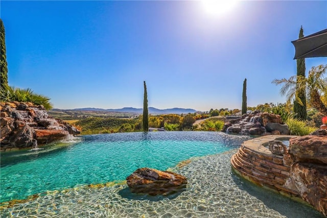 view of pool with an infinity pool and a mountain view