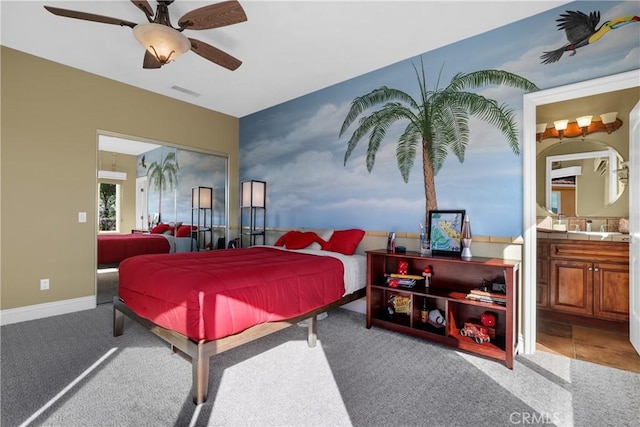 carpeted bedroom with a ceiling fan, connected bathroom, visible vents, and baseboards