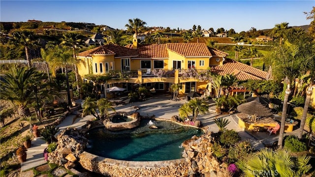 back of house with an outdoor pool, a tile roof, and stucco siding