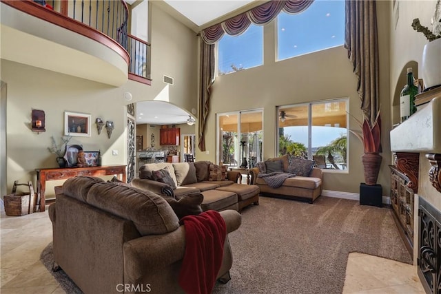 living area featuring light carpet, visible vents, arched walkways, baseboards, and a fireplace with flush hearth