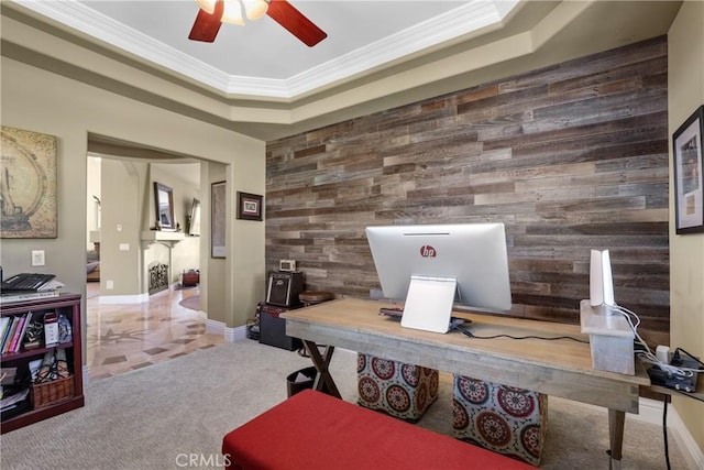 office featuring a tray ceiling, crown molding, an accent wall, carpet flooring, and wooden walls