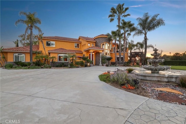 mediterranean / spanish house featuring curved driveway and stucco siding