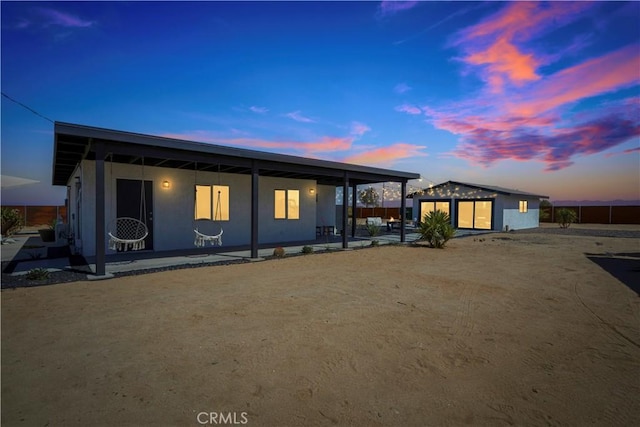 back house at dusk featuring an outbuilding and a patio