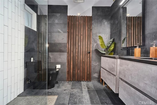 bathroom with a shower, vanity, toilet, and tile walls