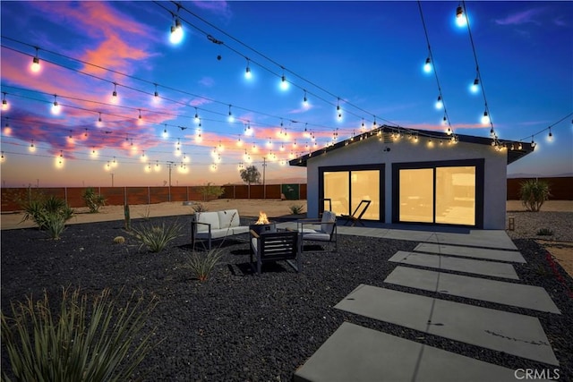 rear view of property with an outdoor living space with a fire pit and a patio