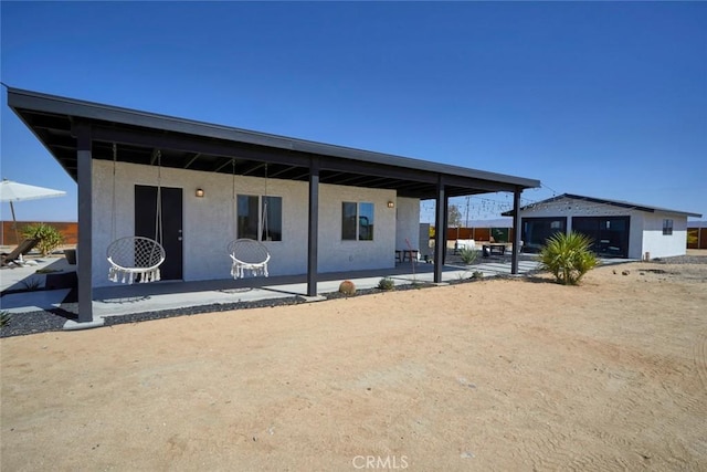 back of property with a patio area, a garage, and an outdoor structure