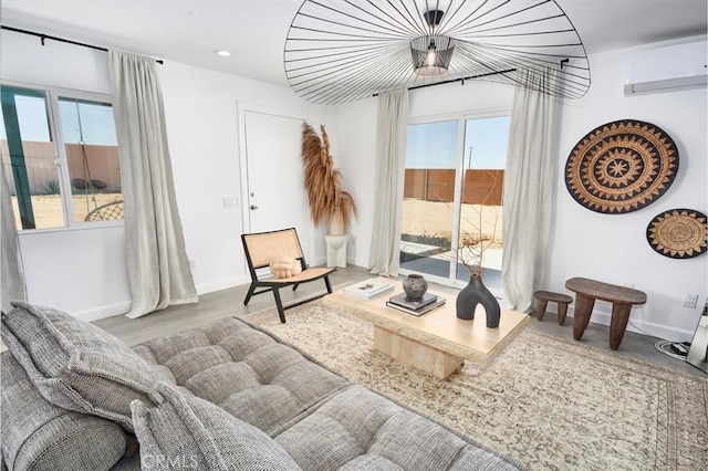 living area featuring concrete floors, an AC wall unit, and a healthy amount of sunlight