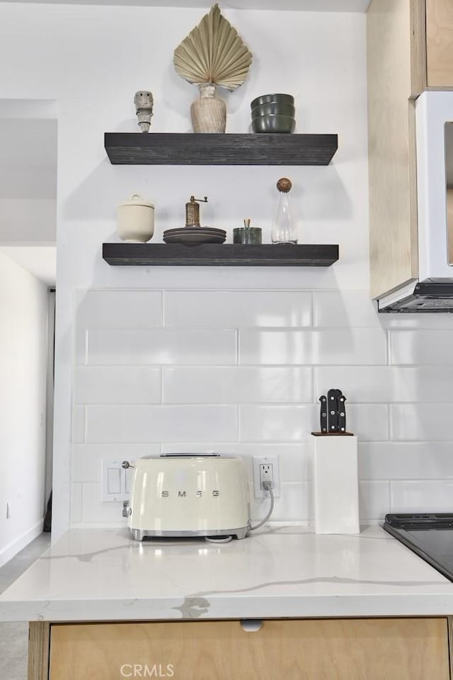 details featuring light brown cabinets, light stone countertops, and backsplash