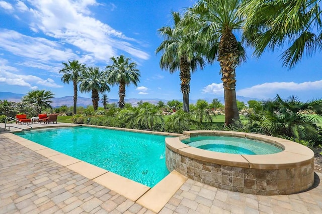 view of swimming pool featuring an in ground hot tub, a mountain view, and a patio area