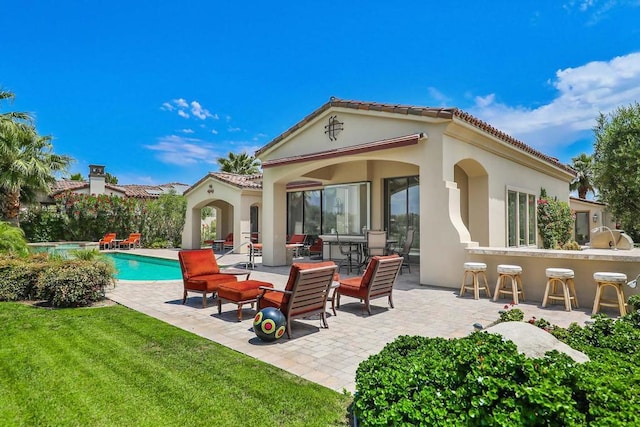 back of property with a bar, a yard, and a patio area