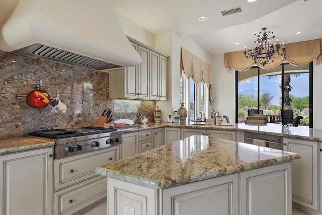 kitchen with stainless steel gas stovetop, sink, light stone countertops, tasteful backsplash, and custom range hood