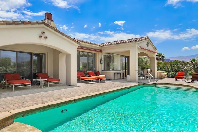 back of property with outdoor lounge area, a mountain view, a patio area, and an outdoor bar