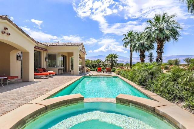 view of pool featuring a mountain view, a patio area, and an in ground hot tub