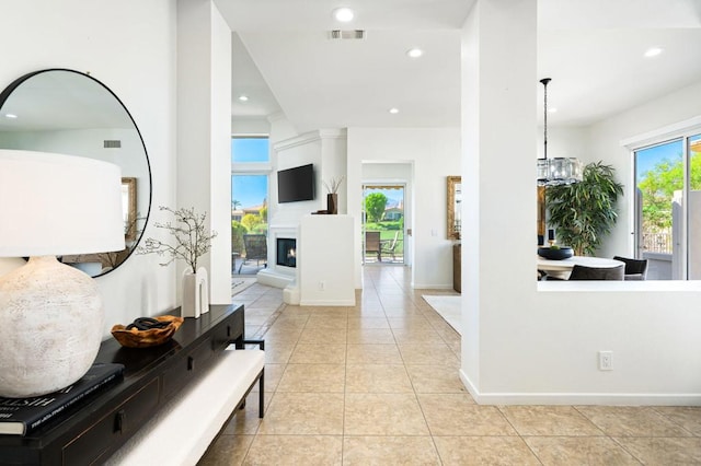 hall with light tile patterned floors and an inviting chandelier