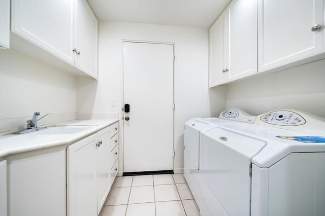 laundry area featuring cabinets, light tile patterned flooring, washing machine and dryer, and sink