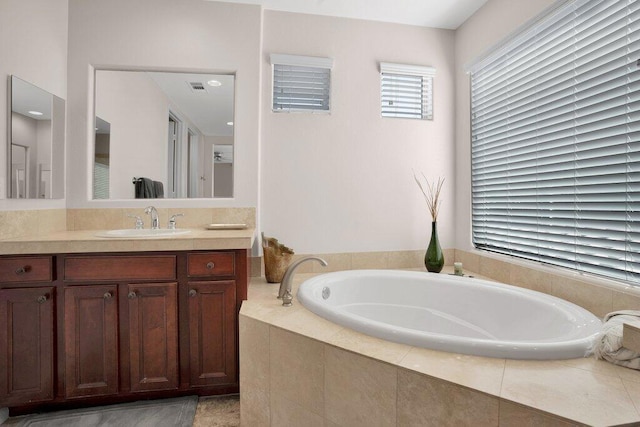 bathroom featuring tiled bath and vanity