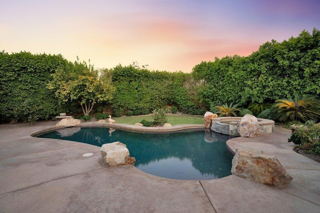 pool at dusk featuring an in ground hot tub