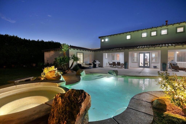 pool at dusk with a jacuzzi, french doors, grilling area, and a patio area