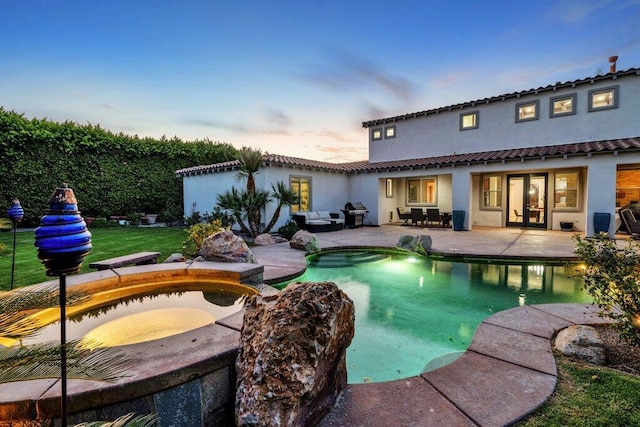 pool at dusk with a patio area, french doors, and a hot tub